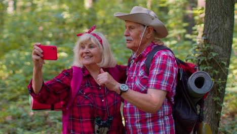 Senior-grandmother-grandfather-blogger-tourists-taking-selfie-photo-portrait-on-smartphone-in-forest