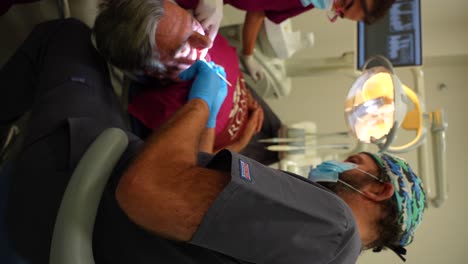 Male-dentist-checking-patient's-denture-under-watchful-eye-of-assistant