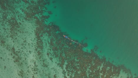 4K-aerial-drone-footage-of-Thai-Longtail-boat-on-shallow-seas,-Phi-Phi-Island,-Thailand,-Asia