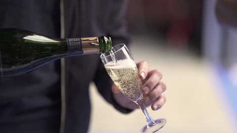 Male-waiter-serving-a-glass-of-french-sparkling-wine-Celene-Champagne-at-an-event,-Close-up