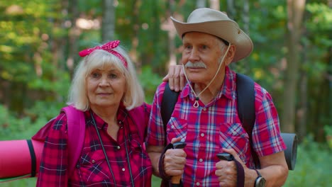 Senior-old-elderly-grandmother-grandfather-training-Nordic-walking-with-ski-trekking-poles-in-wood