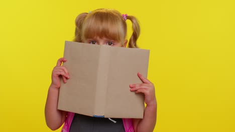 Lovely-teenage-girl-kid-in-school-uniform-wears-pink-backpack-peeping-while-hiding-behind-a-book