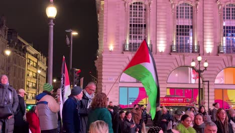 Palestine-protest-in-London-city-centre-United-Kingdom,-waving-flag-night-time