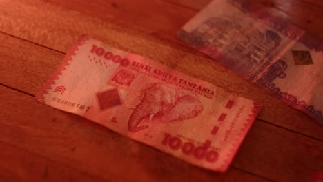 Close-up-Tanzania-shilling-banknotes-on-wooden-table-under-warm-light