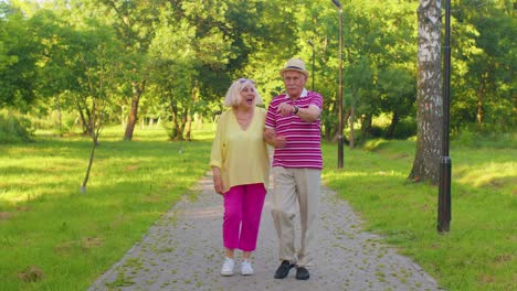 Senior-stylish-pensioners-couple-grandmother-grandfather-walking,-enjoying-time-together-in-park