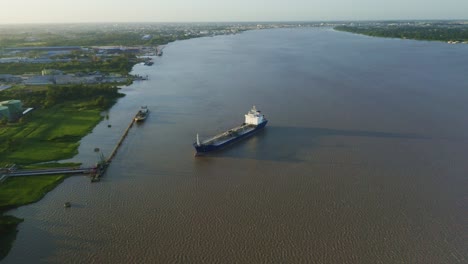 Aerial:-Oil-tanker-ship-getting-in-place-to-dock,-Suriname-river-in-background