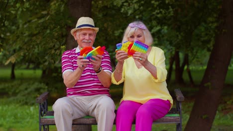 Senior-stylish-grandmother-grandfather-showing-squeezing-anti-stress-push-pop-it-popular-toy-game