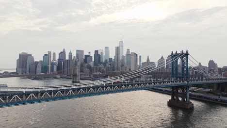 Blue-and-white-painted-details-of-the-Manhattan-bridge-with-NYC-skyling-buildings-under-overcast-sky