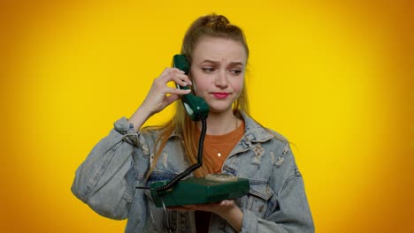 Crazy-sincere-teen-girl-talking-on-wired-vintage-telephone-of-80s,-fooling,-making-silly-funny-faces