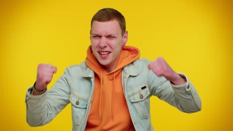 Teen-man-in-denim-jacket-shouting,-raising-fists-in-gesture-I-did-it,-celebrating-success,-winning