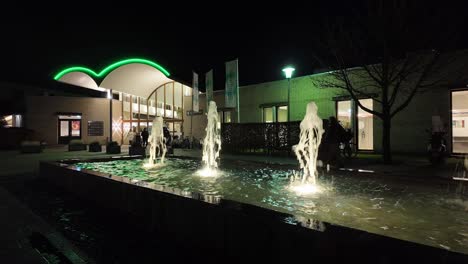 Vista-Nocturna-De-Fuentes-De-Agua-Iluminadas-Frente-A-La-Entrada-Del-Hotel-Arcen-Thermalbad