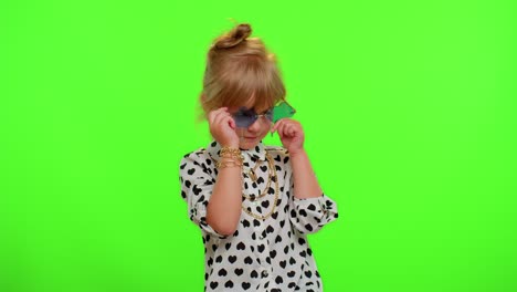 Portrait-of-funny-playful-blonde-child-girl-in-white-black-shirt-wearing-sunglasses,-charming-smile