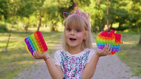 Niño-Pequeño-Y-Elegante,-Niña-Que-Muestra-Burbujas-Blandas-Con-Pantalla-Táctil-De-Silicona,-Juguetes-Sensoriales-Pop-It