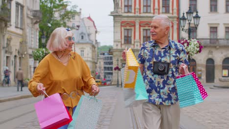 Älterer-Alter,-Stilvoller-Tourist,-Mann-Und-Frau,-Geht-Mit-Bunten-Taschen-Spazieren,-Nachdem-Er-Im-Einkaufszentrum-Auf-Der-Stadtstraße-Eingekauft-Hat