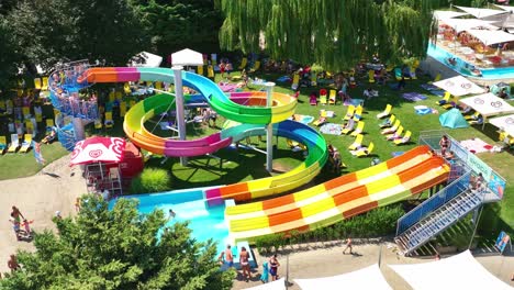 Imágenes-Aéreas-En-Cámara-Lenta-De-Toboganes-De-Agua-Vibrantes-Y-Una-Piscina-En-Un-Parque-Acuático