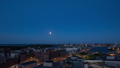 Timelapse-of-the-moon-rising-over-the-cityscape-of-Helsinki,-summer-night-in-Finland