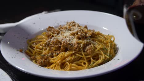 Plate-of-pasta-and-a-glass-of-wine-is-set-before-a-restaurant-guest