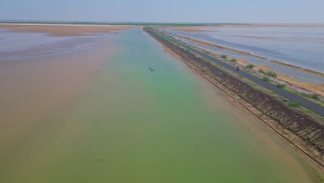 Cinematic-view-of-road-with-salt-water-lake-on-both-side,-clear-water-at-Road-connecting-Khavda-to-Dholavira-in-Kutch,Gujarat,-India-4K-Drone