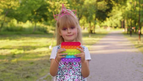 Child-girl-kid-playing-squeezing-anti-stress-pop-it-touch-screen-toys-simple-dimple-game-in-park