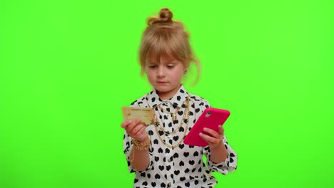 Little-teen-kid-child-girl-using-credit-bank-card-and-smartphone-while-purchases-online-shopping