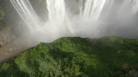 Rainbow-appears-in-mist-from-waterfall-as-water-crashes-down-in-Mexico-Jungle,-aerial