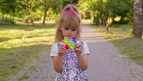 Children-girl-squeezing-presses-colorful-anti-stress-touch-screen-push-pop-it-popular-toy-in-park