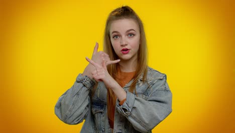 Cheerful-girl-in-denim-jacket-looking-at-camera-doing-phone-gesture-like-says-hey-you-call-me-back