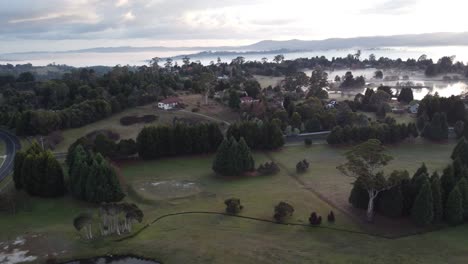 4K-early-morning-aerial-view-of-a-lake-near-a-Swiss-style-village-with-fog-over-a-lake