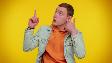 Cheerful-man-in-denim-jacket-looking-at-camera-doing-phone-gesture-like-says-hey-you-call-me-back