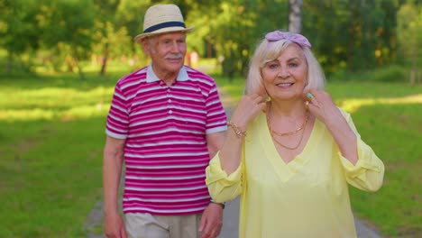 Active-senior-grandfather-pensioner-walking-to-stylish-grandmother-and-making-a-kiss-in-summer-park