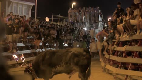 Toro-Con-Bolas-De-Fuego-En-Los-Cuernos-Cavando-En-La-Arena-En-Un-Encierro-Callejero-Con-La-Luna-De-Fondo-En-Sagunto