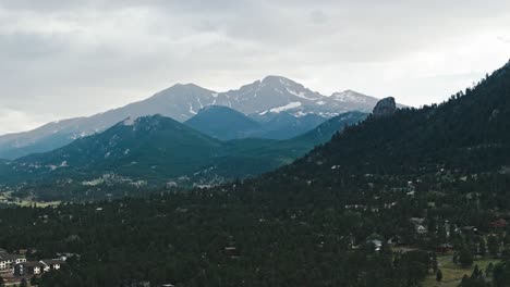 Drone-slowly-ascends-over-alpine-forest-and-Estes-Park-Colorado-to-establish-mountain-peak