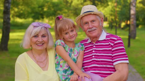 Little-granddaughter-together-with-senior-grandmother-and-grandfather-in-park,-family-relationship