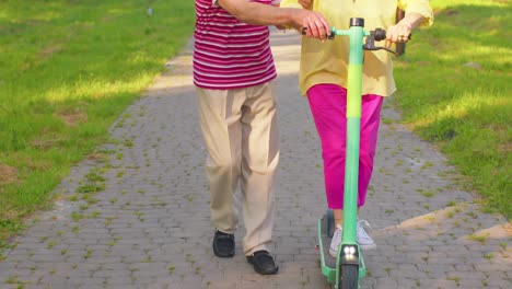 Senior-old-stylish-tourists-grandmother,-grandfather-using-electric-scooter-enjoying-learning-ride