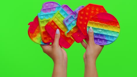 Girl-hands-showing-many-pop-it-sensory-anti-stress-bubbles-squish-toys-game-isolated-on-chroma-key