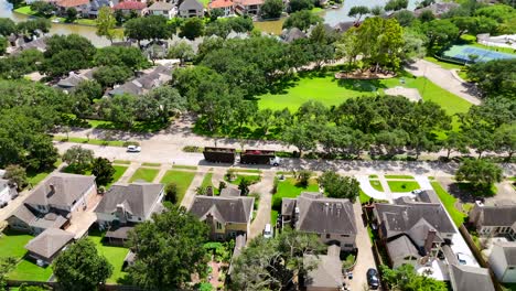 An-aerial-view-of-a-full-tree-truck-in-motion,-driving-through-a-suburban-neighborhood