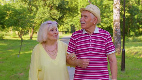 Pareja-De-Turistas-Mayores-Y-Elegantes-Abuela,-Abuelo-Dando-Un-Paseo-Y-Hablando-En-El-Parque-De-Verano