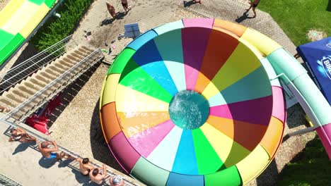 Aerial-shot-of-woman-enjoying-a-colorful-water-slide-at-aquapark