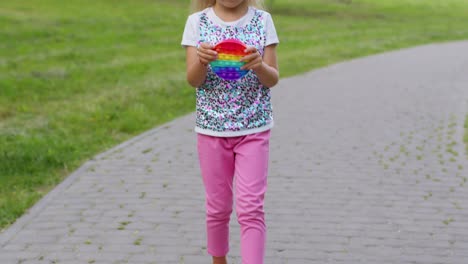 Child-girl-kid-playing-push-pop-it-bubble-fidget-toy-in-park,-stress-anxiety-relief-squeeze-sensory