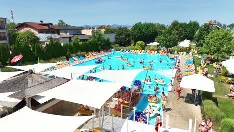 Aerial-footage-of-an-aquapark-featuring-spacious-pools,-sun-loungers,-and-shaded-areas