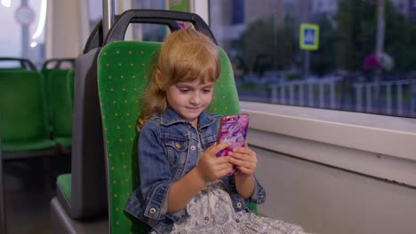 Girl-playing-on-smartphone,-chatting,-texting,-browsing-social-media-while-traveling-by-tram-to-city