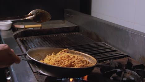 Slow-motion-of-a-chef-flipping-traditional-dish-of-spaghetti-with-red-tomato-sauce-on-pan