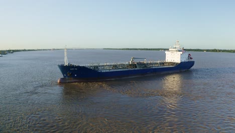 Aerial:-Oil-tanker-ship-getting-in-place-to-dock-in-Suriname-river,-water-ripples