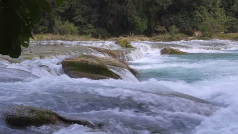 Heavy-flowing-water-rushes-along-rocks-churning-with-whitewash-in-Mexico-jungle,-Tamul-Waterfall