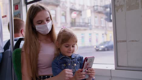 Mujer-Cansada-Y-Soñolienta-Con-Su-Hija-Yendo-A-Casa-En-Autobús-Después-De-Un-Duro-Día-De-Trabajo,-Un-Niño-Juega-En-Un-Teléfono-Inteligente