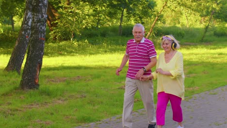 Pareja-De-Ancianos-Con-Estilo-Familia-Abuela-Abuelo-Bailando,-Caminando-Escuchando-Música-En-El-Parque-De-Verano