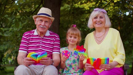 Ältere-Großmutter,-Großvater-Und-Enkelin-Halten-Anti-Stress-Pop-It-Spielzeugspiele-Im-Park