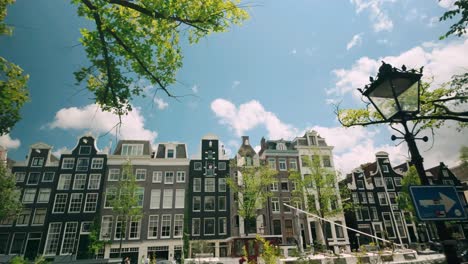 Dolly-travel-shot-of-Amsterdam's-famous-historic-canal-houses,-showcasing-the-iconic-architecture-under-a-clear-blue-sky