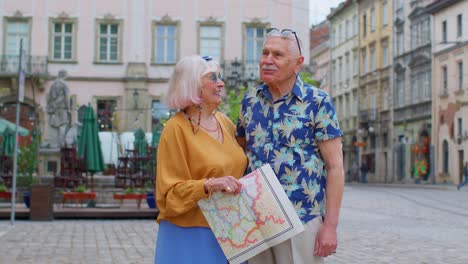 Ältere,-Stilvolle-Touristen,-Mann-Und-Frau,-Unterhalten-Sich-Auf-Der-Straße-Und-Halten-Eine-Papierkarte-In-Der-Altstadt