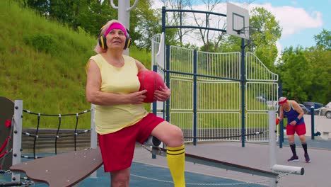 Senior-woman-grandmother-after-sport-basketball-training-sitting-listening-music-on-playground-yard